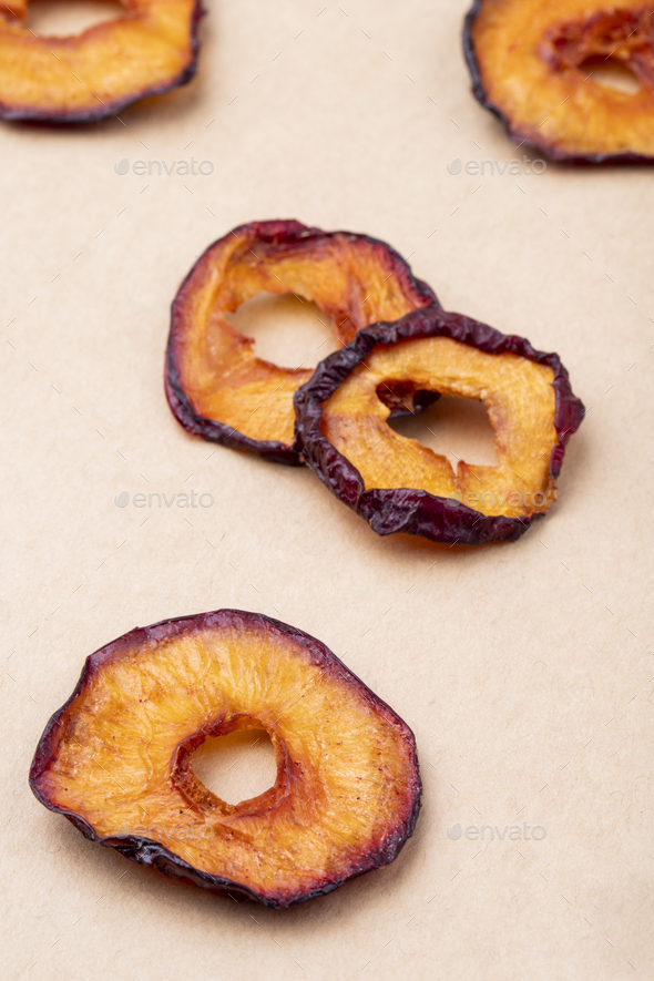 side view of dried plum slices isolated on brown paper texture